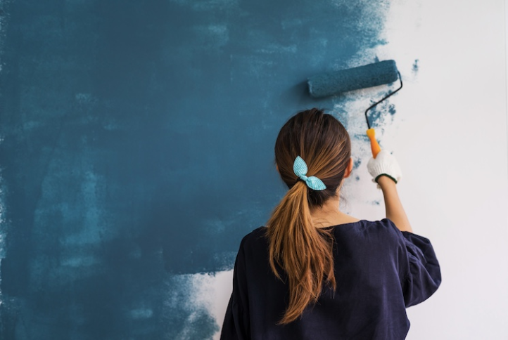 Mujer pintando la pared, cambiando el color de blanco a azul