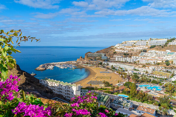 Imagen de una playa de canarias masificada, rodeada de hoteles por todas partes