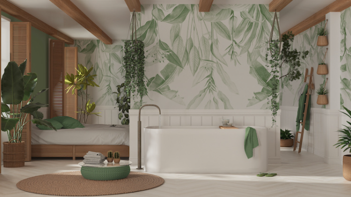 Cuarto de baño con pared decorada con papel pintado blanco con motivos de hojas verdes. Bañera blanca con líneas sencillas.