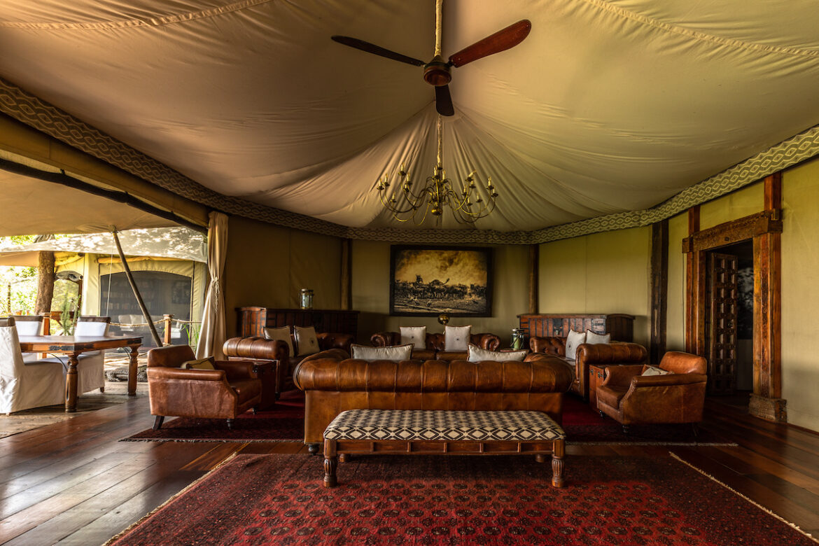 Salón amueblado estilo safari, con sofás de piel y ventilador de madera