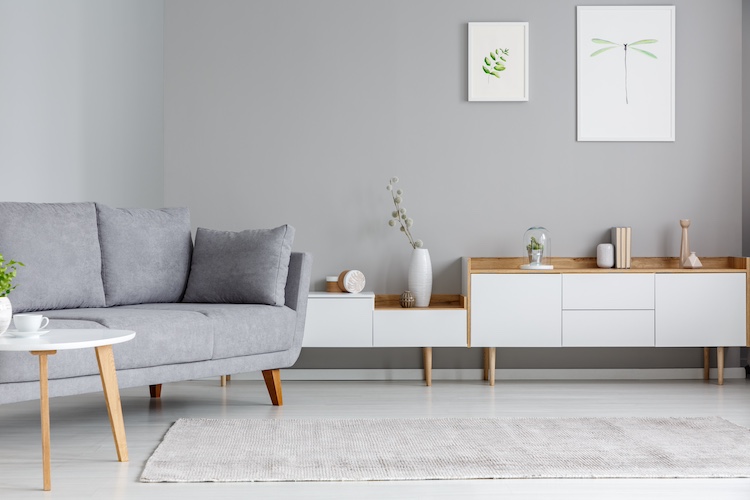 Habitación decorada con pared gris, sofá gris y mueble bajo en blanco y madera