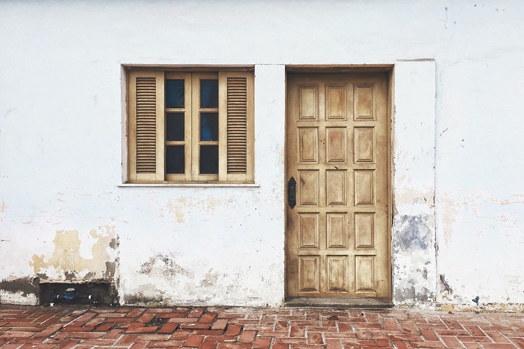 Fachada blanca en mal estado y puerta de madera