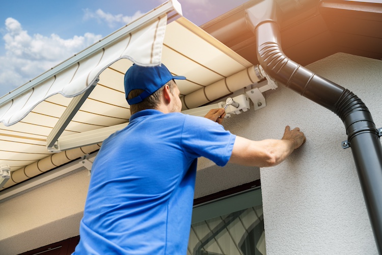 Hombre instalando un toldo en una vivienda