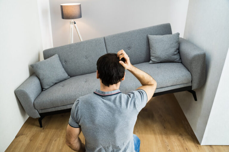 Hombre intentando colocar un sofá que no cabe en la habitación