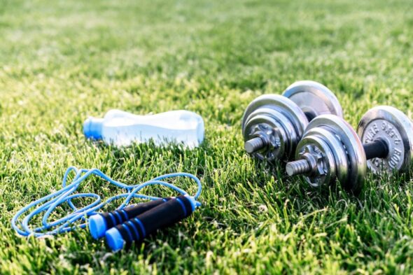 Pesas, comba y botella de agua en el jardín