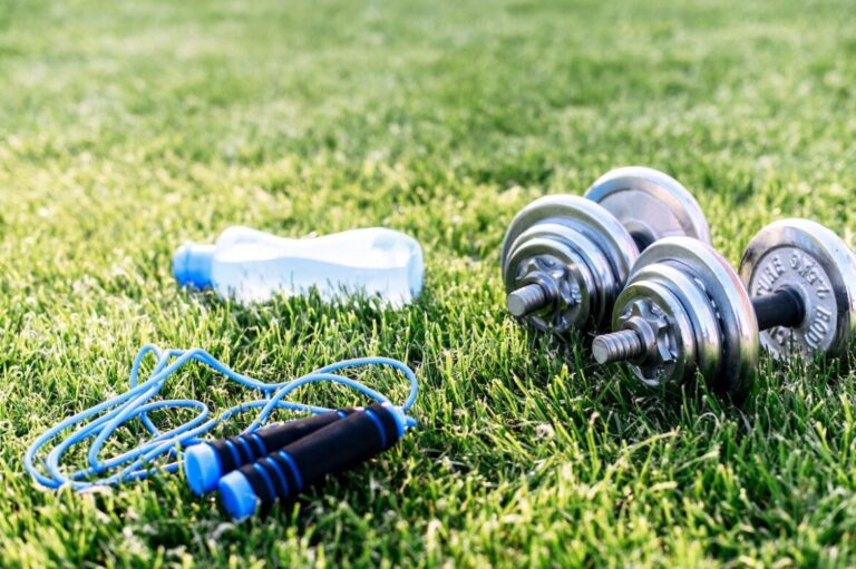 Pesas, comba y botella de agua en el jardín