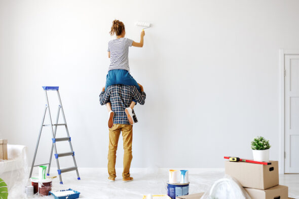 Pareja realizando tareas de mantenimiento, pintando una pared blanca