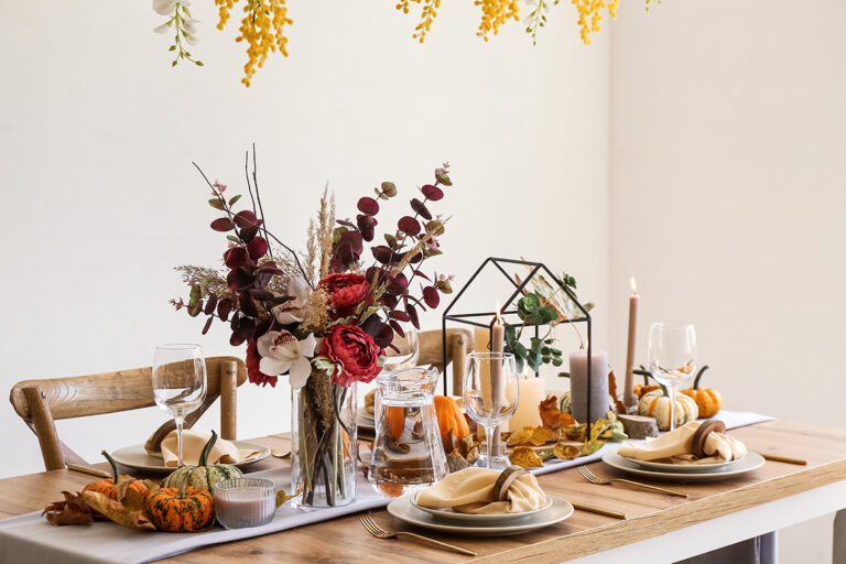 Mesa con servilletas de tela, flores secas y jarra de cristal