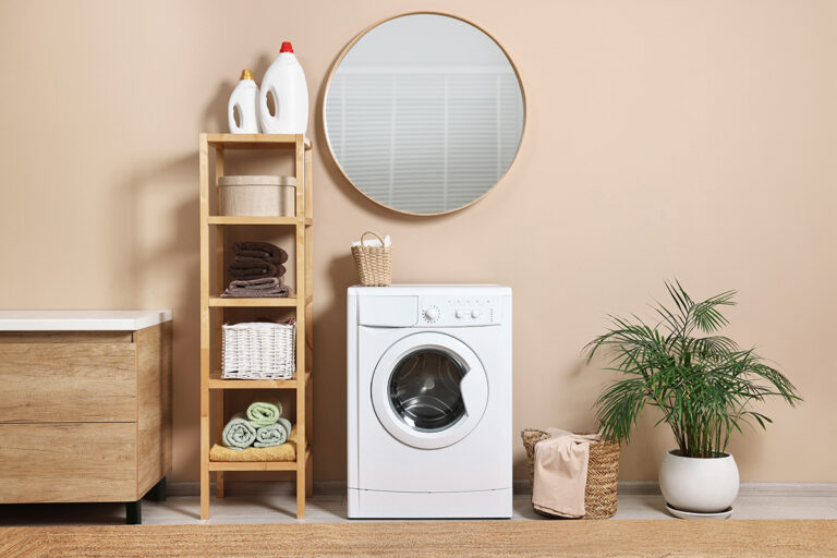 Lavadora en el baño, junto a estantería de madera y espejo de madera