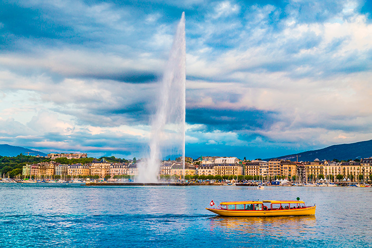 Lago de Ginebra con ciudad al fondo y gran fuente de agua.